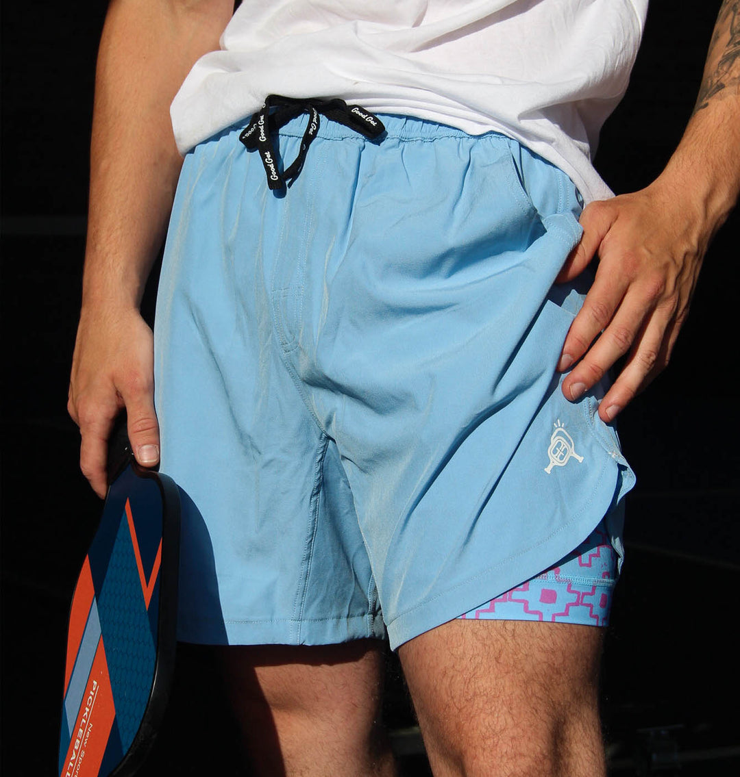 Person wearing light blue swim shorts with a geometric pattern on the inside, holding a paddle.