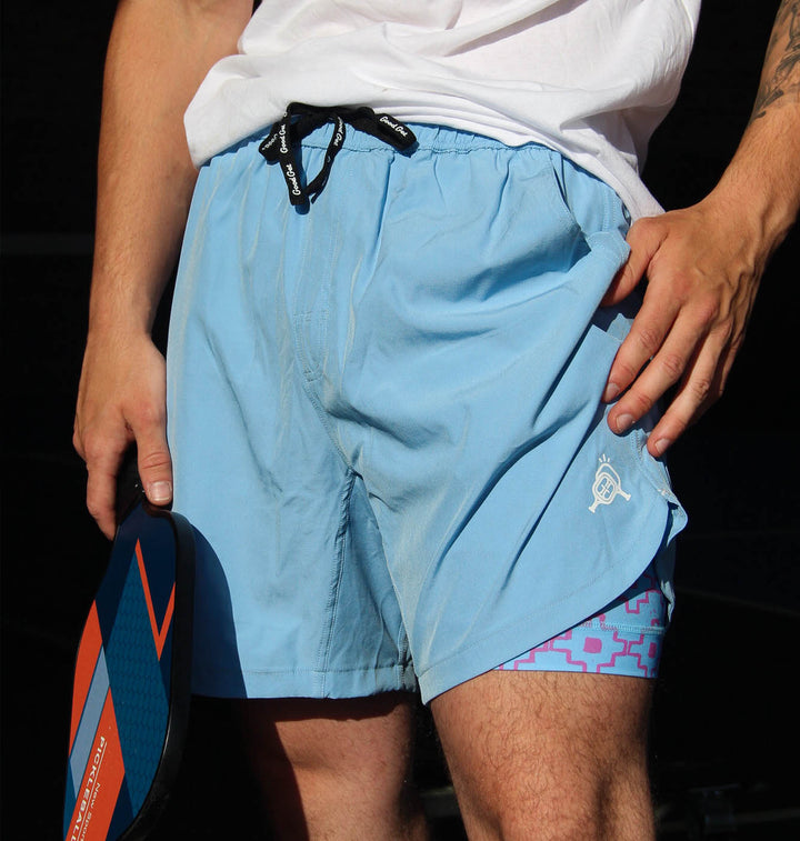 Person wearing light blue swim shorts with a geometric pattern on the inside, holding a paddle.